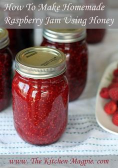 jars filled with raspberry jam sitting on top of a table