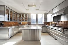 a large kitchen with stainless steel appliances and counter tops on the walls, along with an island