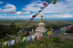 many colorful flags are flying in the air above a mountain top with a sky background