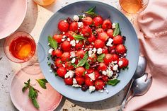 a blue bowl filled with strawberries and feta cheese on top of a table