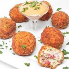 several crab cakes on a plate with a small bowl of sauce