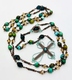 a long beaded necklace with a dragonfly brooch and matching beads is displayed on a white surface