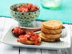 a plate topped with toasted bread and sliced tomatoes next to a bowl of salad