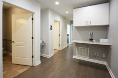 an empty room with white cabinets and wood floors