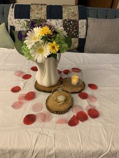 a white vase filled with flowers sitting on top of a bed