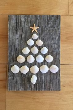 a christmas tree made out of seashells on a wooden board