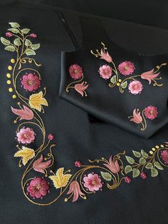 an embroidered black cloth with pink flowers on it