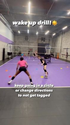 two people are playing tennis in a large room with purple flooring and white walls