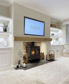 a fireplace with a flat screen tv mounted above it's mantle and logs on the floor