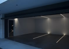 an empty room with white walls and lights on the ceiling is lit up at night