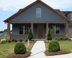 a blue house with brown trim and trimmed front yard