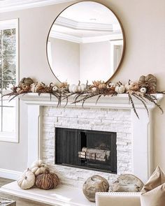 a living room with a fire place and mirror on the fireplace mantel, decorated for fall