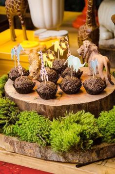 there are cupcakes that look like animals on top of the tree stump and grass