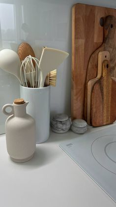 kitchen utensils and wooden cutting board on counter in white room with stovetop