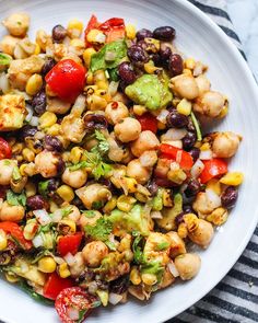 a white bowl filled with corn, black beans and tomatoes on top of a striped table cloth