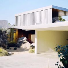 a modern house with large rocks in the front yard