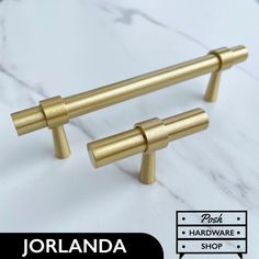 two brass handles on a white marble countertop with the words jorland hardware shop below it