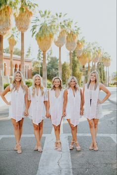 the bridesmaids are wearing white dresses and posing for a photo in front of palm trees