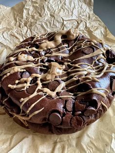 a chocolate cake covered in icing and drizzles on top of wax paper