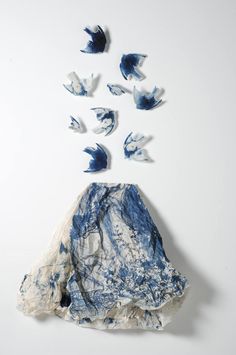 blue and white paper birds are flying over the top of a piece of clothing that has been torn off