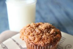 a muffin sitting on top of a white plate next to a glass of milk