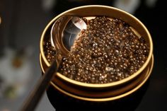 a bowl filled with lots of brown stuff on top of a table next to a spoon