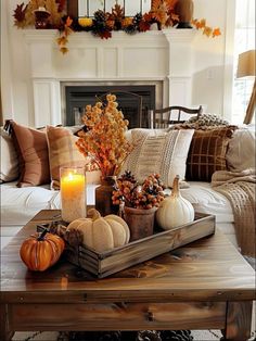 a living room filled with furniture and a fire place covered in fall decorations on top of a coffee table