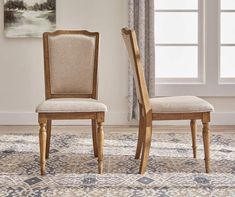 two wooden chairs sitting next to each other on top of a carpeted floor in front of a window