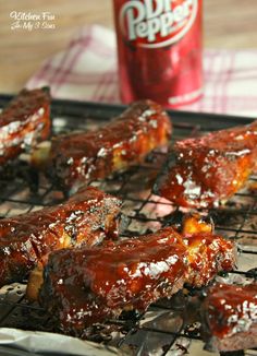 barbecue ribs on a grill next to a can of pop pop soda and a glass of coke