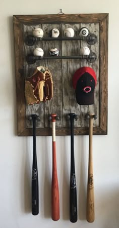 three baseball bats are hanging on the wall next to a hat and glove rack that is made out of wood