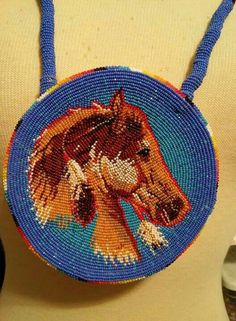 a beaded purse with a horse on it's front and back side hanging from a mannequin torso