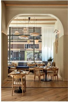 an arched doorway leads into a restaurant with wooden tables and chairs in the foreground