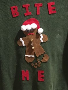 a green sweater with an image of a gingerbread man wearing a santa claus hat