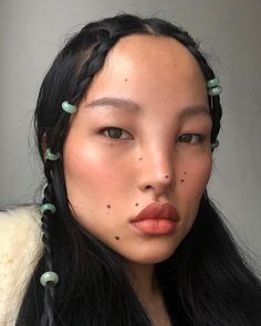 a woman with long black hair and green beads on her head is looking at the camera