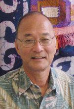 an older man wearing glasses standing in front of a wall with colorful art on it