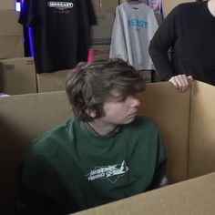 two people standing in a room with boxes on the floor and one person sitting down