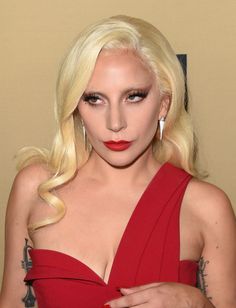 lady in red dress with long blonde hair and black eyeliner posing for the camera