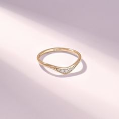 a yellow gold ring with three diamonds on the top and bottom, sitting on a white surface