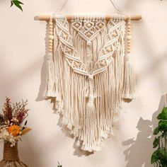 a macrame hanging on a wall next to a vase with flowers