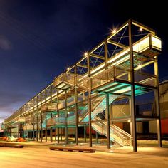 an empty parking lot at night with lights on the building and stairs leading up to it