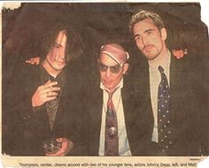 three men in suits and ties are posing for a photo with one man wearing a bandana