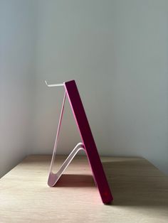 a pink sculpture sitting on top of a wooden table next to a white wall and window