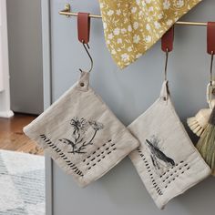 two kitchen towels hanging from hooks on a wall