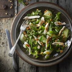 a salad with cucumbers, onions and parsley in a bowl on a wooden table