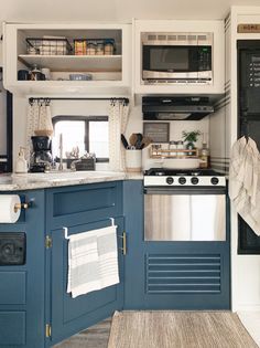 a kitchen with blue cabinets and stainless steel appliances, including a stove top oven in the center