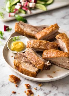 some meat is on a white plate with mustard and ketchup next to it