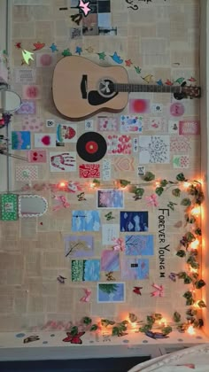 a bulletin board is covered with pictures and string lights as well as an acoustic guitar