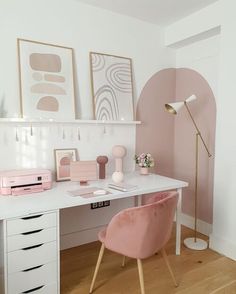 a white desk topped with a pink chair next to a wall mounted art work area