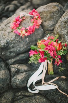 a bouquet of flowers sitting on top of a rock next to a white ribbon tied around it