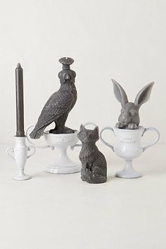 three ceramic figurines of rabbits and birds sitting on top of cups with candlesticks